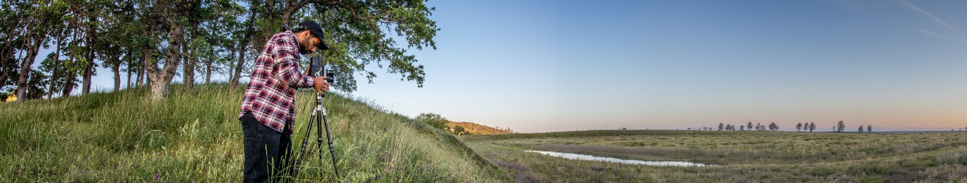 A researcher using a tripod beside a wetland